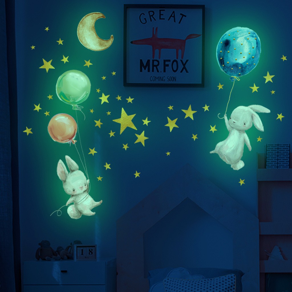 Sød selvlysende wallsticker med to små kaniner der svæver med balloner, omgivet af masser af stjerner.